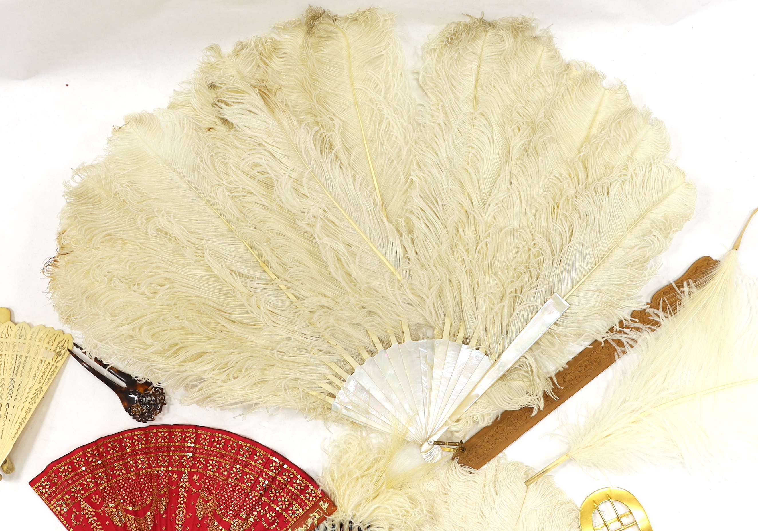 A Regency sequin and horn fan, a bone brise fan, a large white feather fan and a similar miniature fan and hat ornament two hair combs, etc